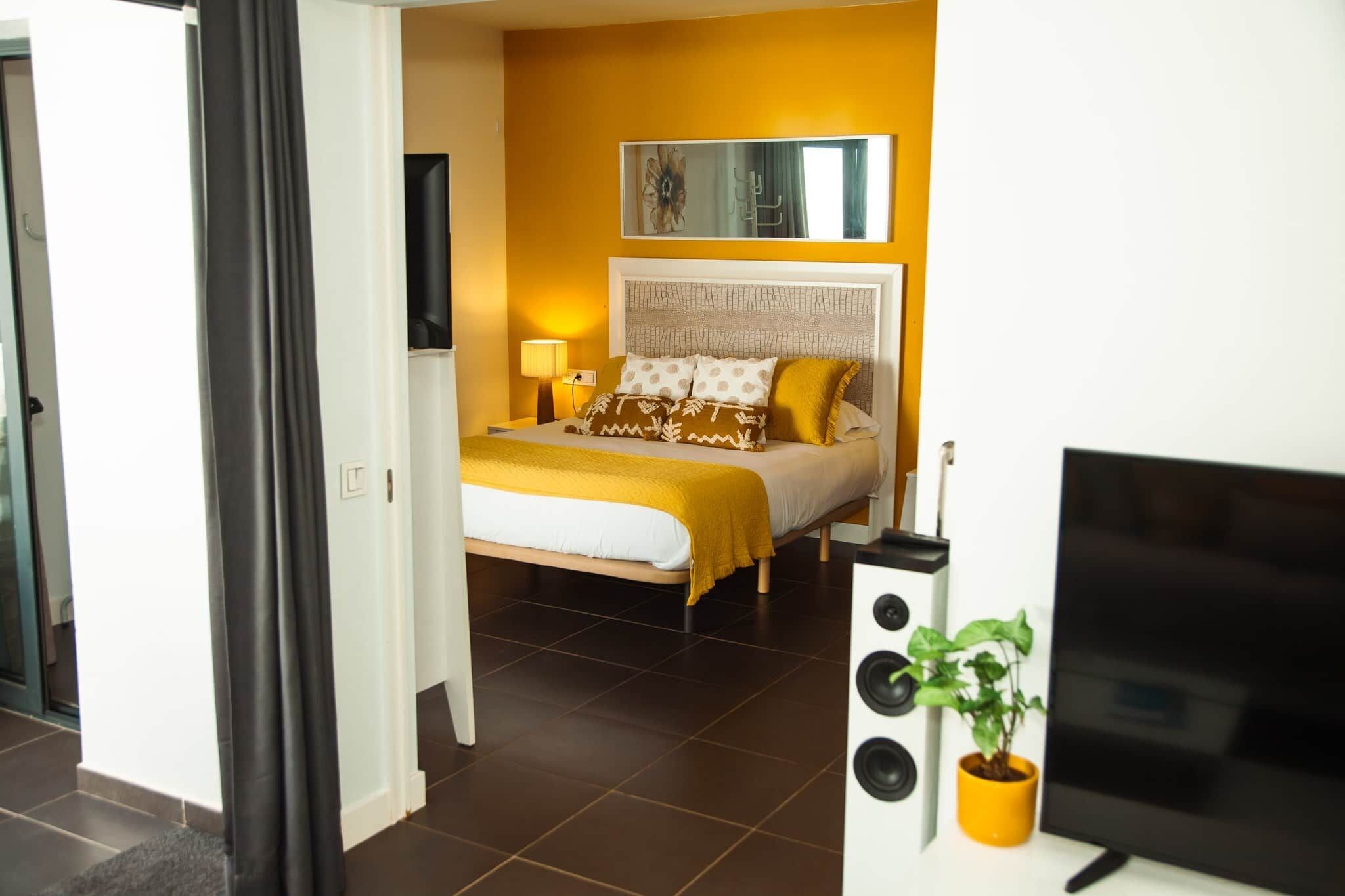 Una habitación de hotel con una cama, un televisor y una planta en maceta.