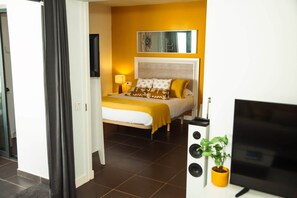 A hotel room with a bed, a television, and a potted plant.
