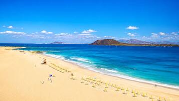 Una playa cerca, sillas reclinables de playa, toallas de playa