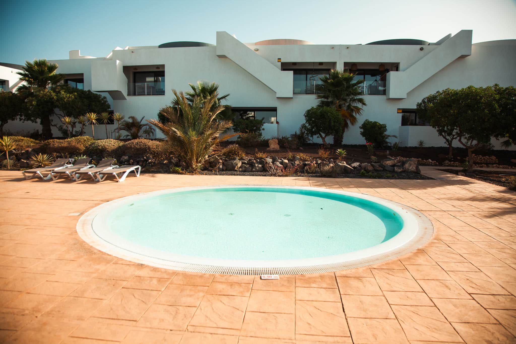 A swimming pool with lounge chairs and a modern building in the background.