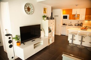 A modern kitchen with white cabinets, a built-in oven, and a bar area with stools.
