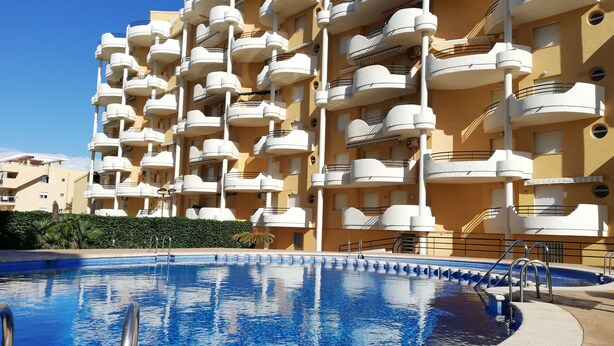 A multi-story hotel with balconies, a swimming pool, and a clear blue sky. - Les Motes 2º Solo Familias! (Xeraco Playa)