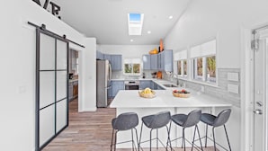 A modern kitchen with a large island, bar stools, and a view of the adjacent dining area.