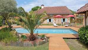 A pool area with wooden deck, lounge chairs, and a building with a tiled roof. - Villa 230 M2 With Garden  Lac De Léon And Ocean (Léon)