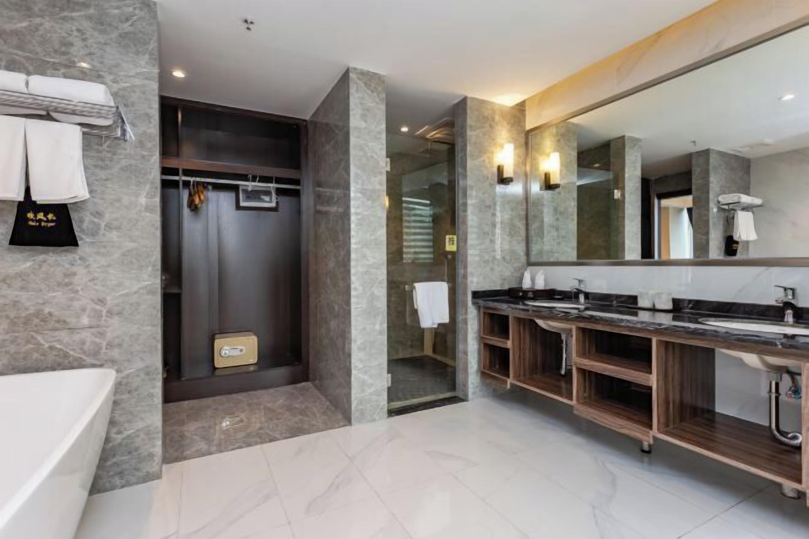 A modern bathroom with a large mirror, two sinks, a shower, and a towel rack.
