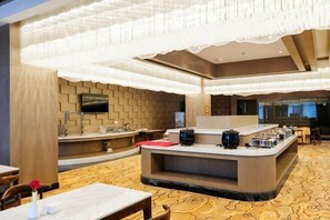 A modern hotel lobby with a central bar, seating areas, and a patterned carpet.