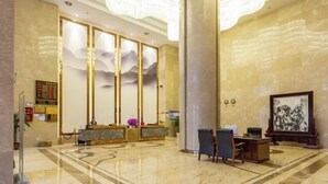 A spacious lobby with a reception desk, seating area, and a large painting on the wall. - Tianrui Hotel (Yanhe)