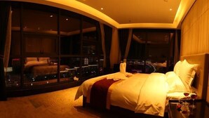 A hotel room with a large bed, a nightstand, and a view through large windows. - Tianrui Hotel (Yanhe)