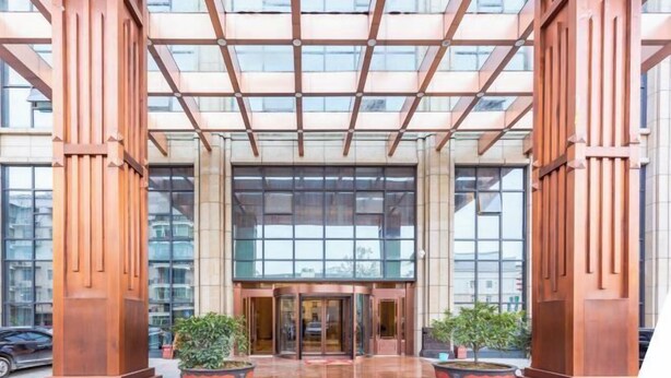 A modern building entrance with a glass facade, large doors, and two potted plants. - Tianrui Hotel (Yanhe)