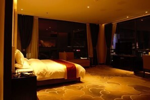 A hotel room with a bed, a desk, and a view of the cityscape. - Tianrui Hotel (Yanhe)
