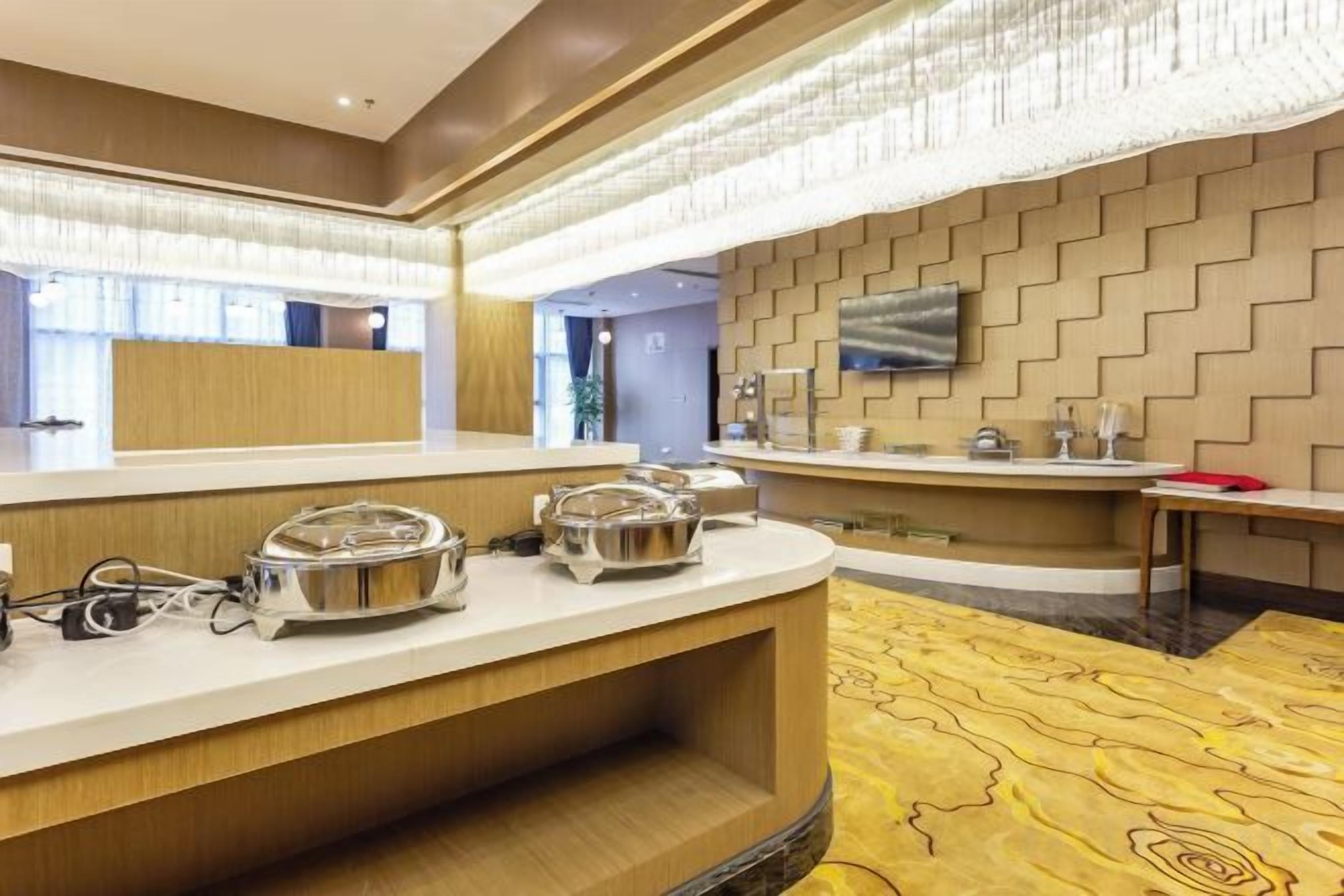 Un hall d’hôtel comprenant un comptoir d’accueil, un espace buffet et un grand miroir.