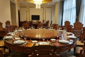 A conference room with a round table, chairs, and a television screen. - Tianrui Hotel (Yanhe)
