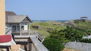 Une structure en bois située sur la côte, dotée d’une terrasse et d’un petit pavillon, et offrant une vue sur la plage et l’océan.
