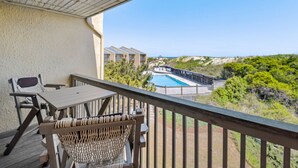 Un balcon donnant sur une piscine et sur des bâtiments en arrière-plan.
