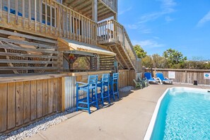 A wooden deck with a pool, blue chairs, and a barbecue area. - Sea Blue: 4-Bedroom Oceanside w/ Private Pool and Hot Tub (Corolla)