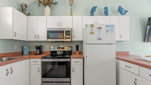 Una cocina moderna con gabinetes blancos, electrodomésticos de acero inoxidable y una isla central.