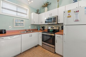 A compact kitchen with white cabinets, a microwave, an oven, and a refrigerator.