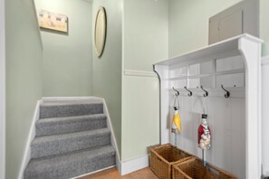 Eine Treppe führt zu einer Empfangshalle mit Kleiderhaken und Körben.