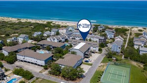 Vista aérea de una comunidad residencial con varias casas, piscina y cancha de tenis.
