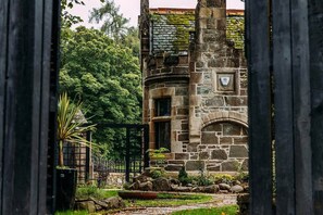 A stone building with a circular window and a door, surrounded by greenery and a stone pathway. - Spacious South Lodge with Hot Tub Balloch (Balloch)