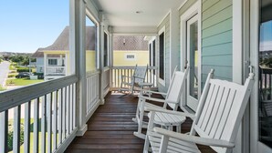 A wooden porch with white rocking chairs and a view of neighboring houses. - Anchors Down: Private Pool | Hot Tub | Rec Room (Corolla)