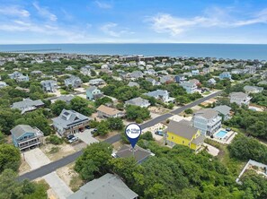 An aerial view of a residential area with houses, a pier, and a beach in the background. - Kiki's Retreat: Walk to Duck Village | Pets OK (Duck)