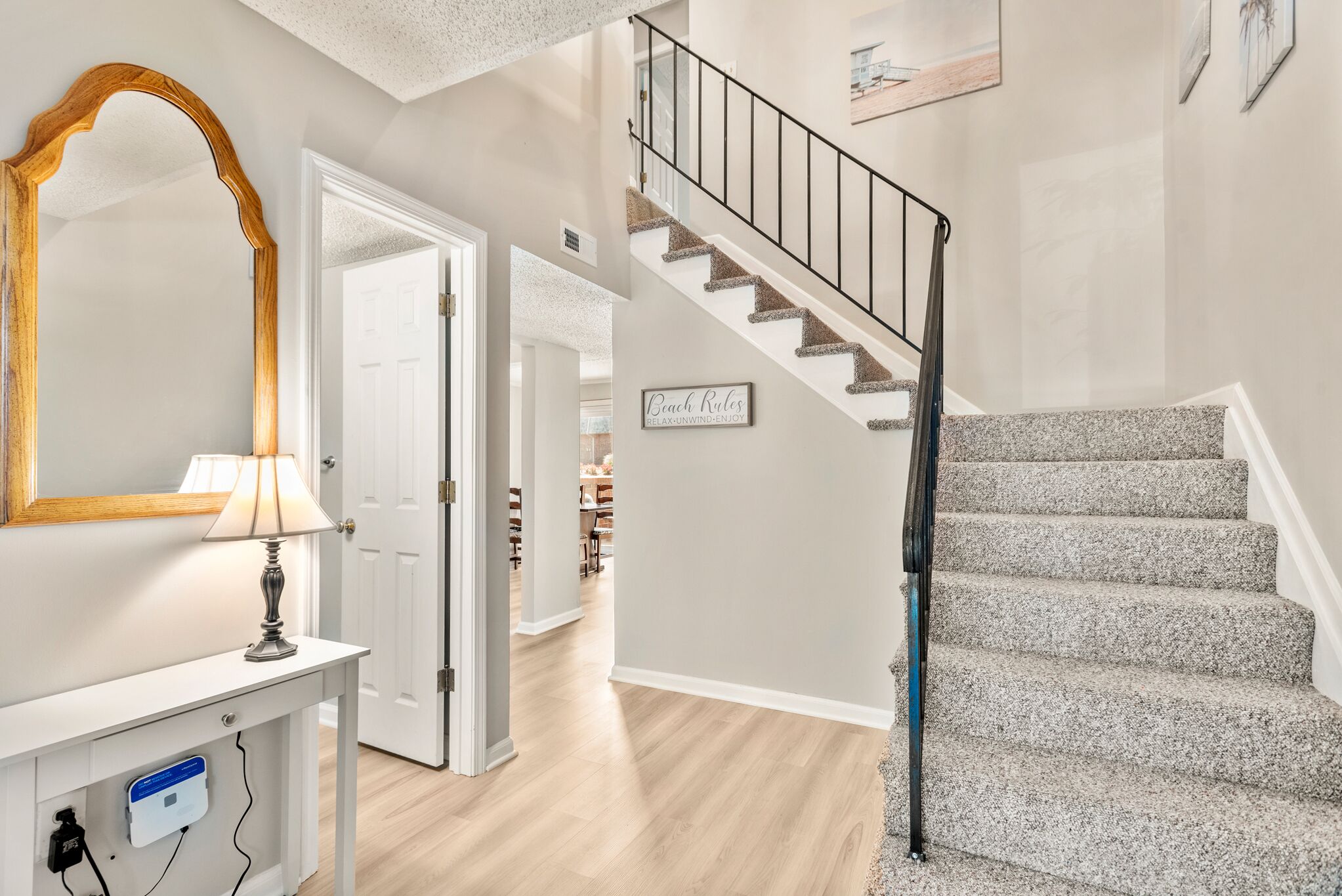 A staircase with a metal railing, a wooden-framed mirror, and a wall-mounted lamp.