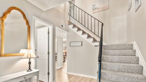 Un escalier avec une rampe en métal, un miroir à cadre en bois et une lampe fixée au mur.