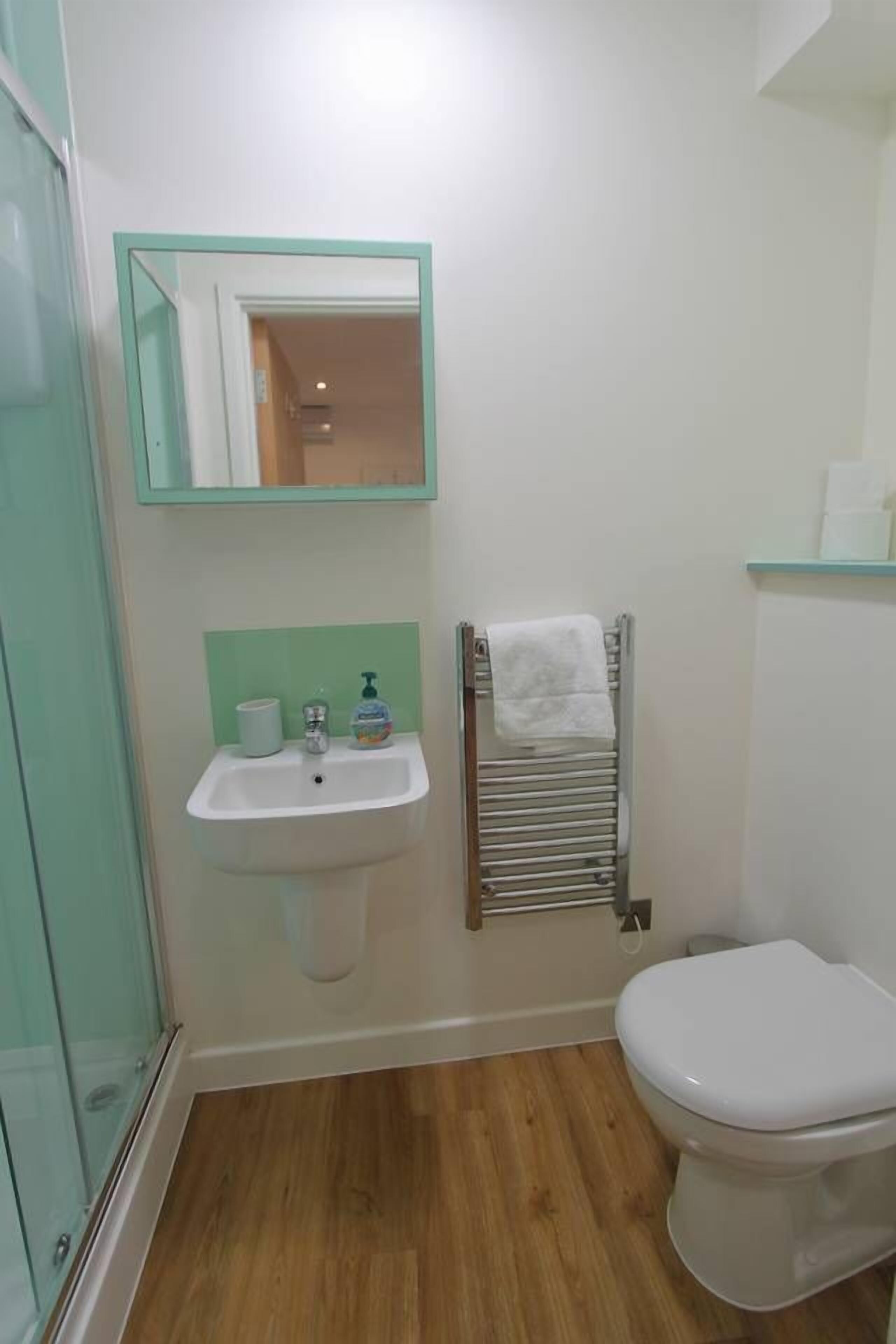 A bathroom with a white sink, a mirror, a towel rack, and a toilet.