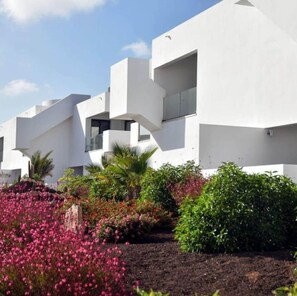 A modern building with white exterior walls and multiple balconies.