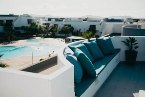 A rooftop terrace with a pool, a white outdoor sofa with teal cushions, and a potted plant. - Luxury Penthouse: Terrace, Hot Tub and Sauna (La Oliva)