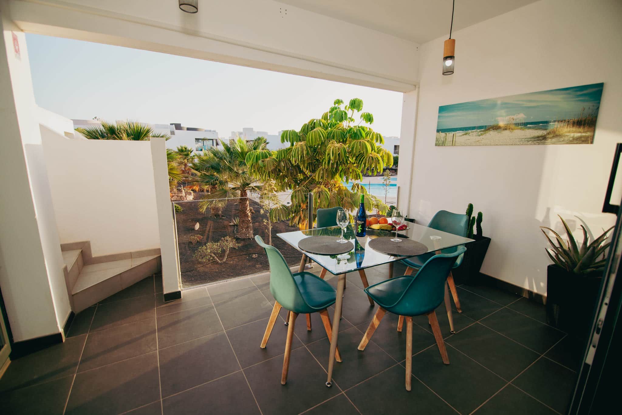 A dining area with a glass table, chairs, and a view of the outdoors.