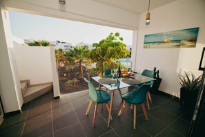 A dining area with a glass table, chairs, and a view of the outdoors.