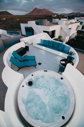 Eine Dachterrasse mit Whirlpool, Sitzgelegenheit und Blick auf einen Berg.