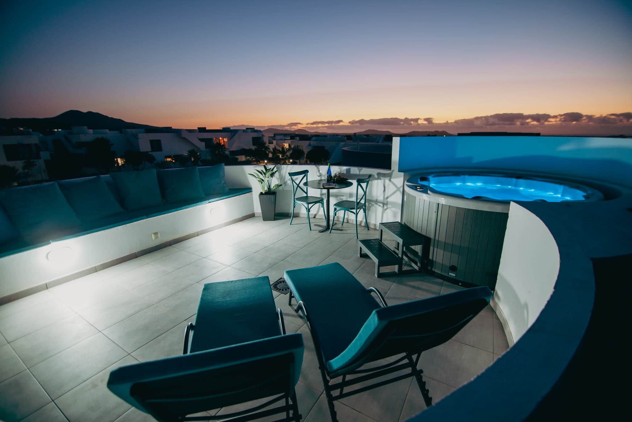 A rooftop terrace with a swimming pool, lounge chairs, and a table.