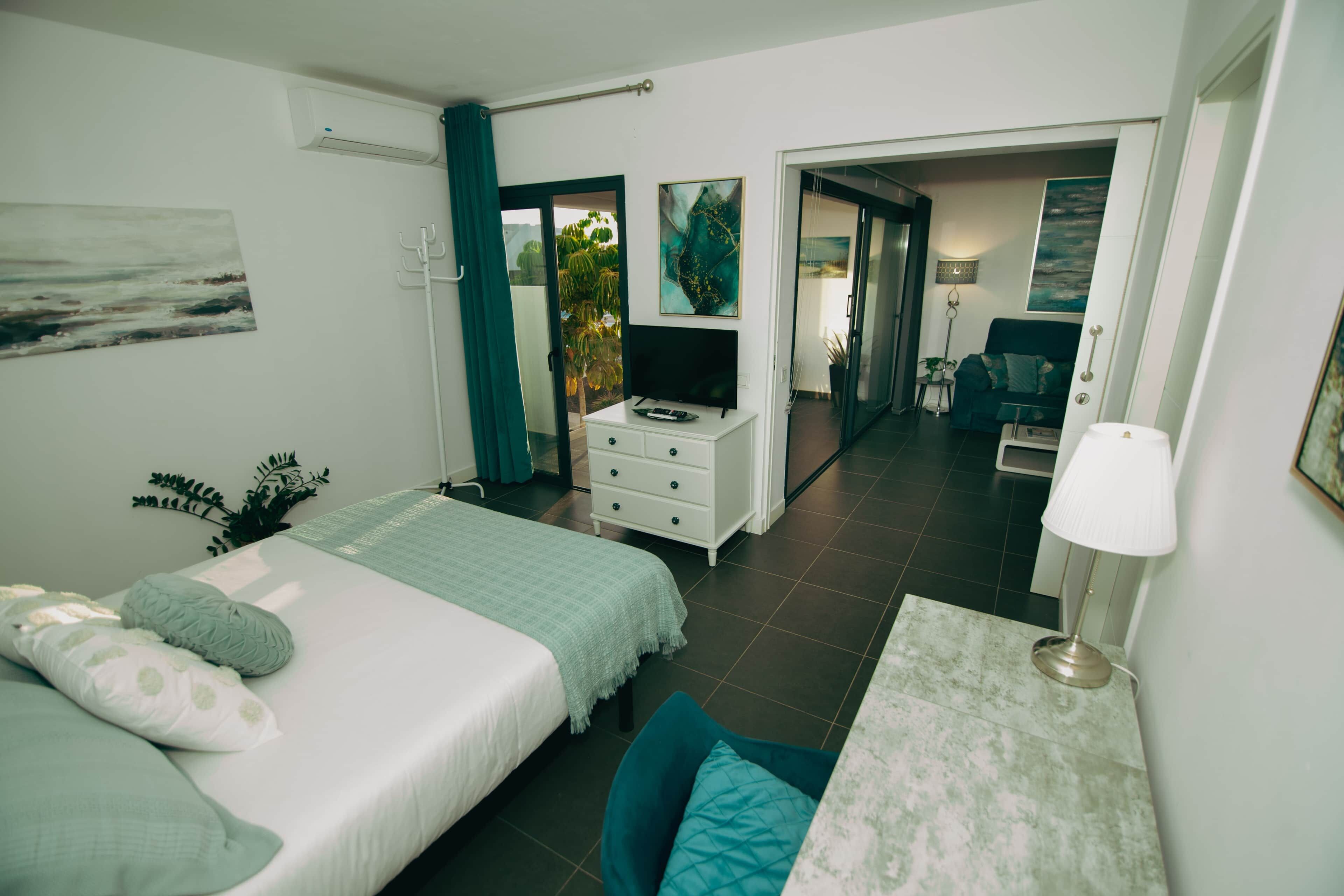 Une chambre à coucher avec un lit, un bureau, une télévision et une vue sur l’extérieur.