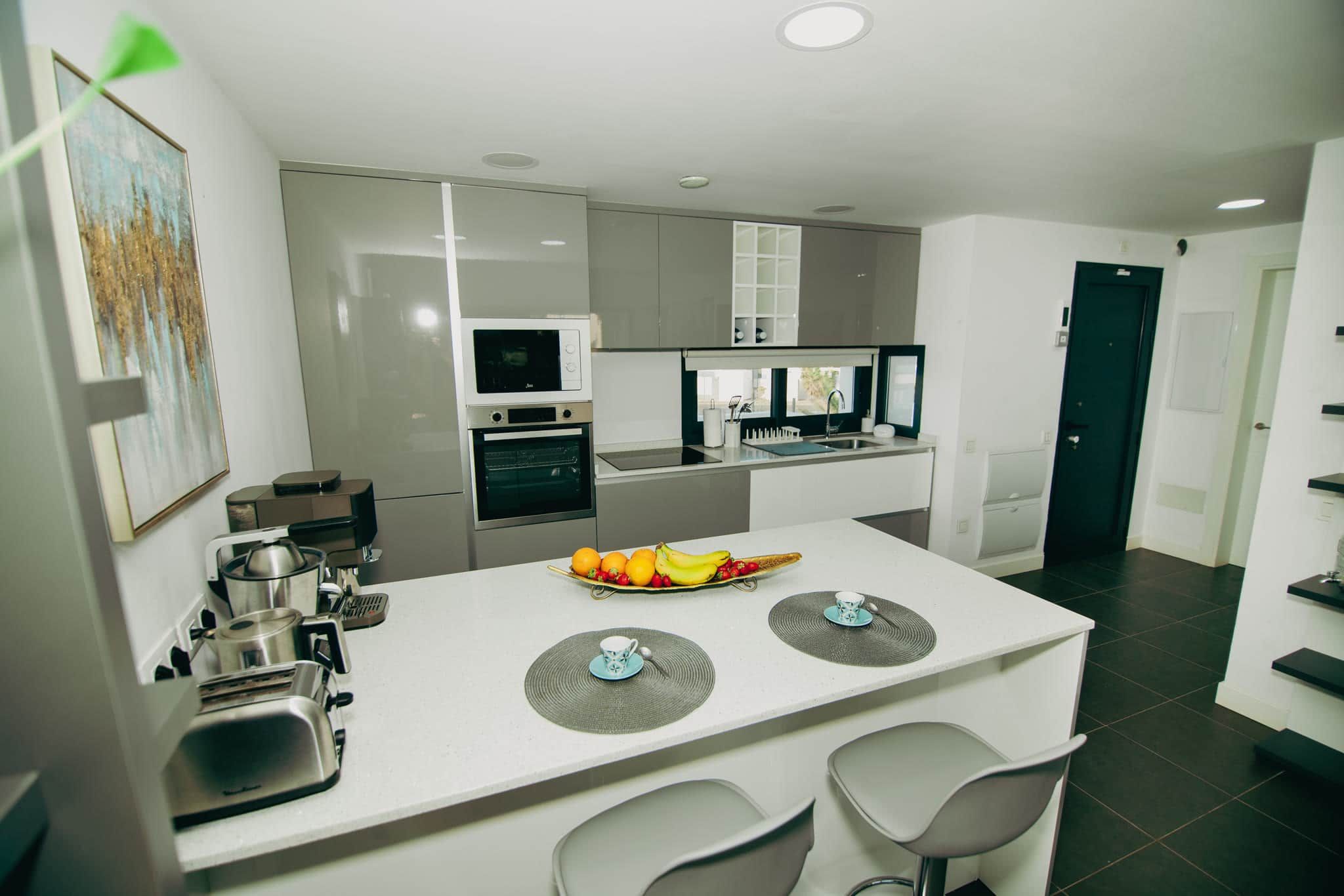 Una cocina moderna con una isla central, electrodomésticos integrados y un comedor con sillas.