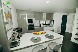 A modern kitchen with a central island, built-in appliances, and a dining area with chairs. - Luxury Penthouse: Terrace, Hot Tub and Sauna (La Oliva)