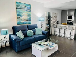 Ein modernes Wohnzimmer mit einer Couch, einem Couchtisch und einer Küchenzeile mit Barhocker.