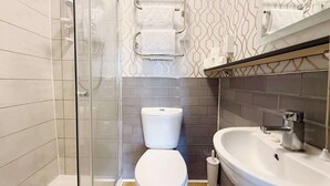 Un baño moderno con cabina de ducha de vidrio, inodoro y lavabo con espejo.