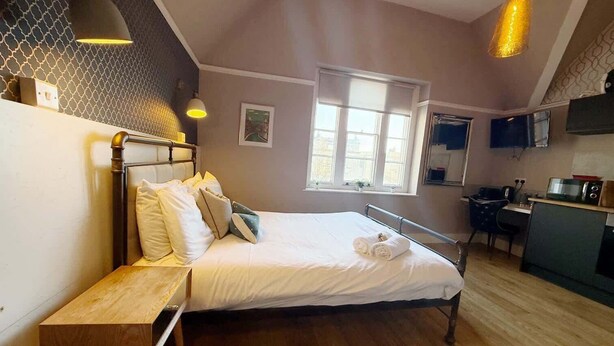 Un dormitorio con cama, mesita de noche y ventana.