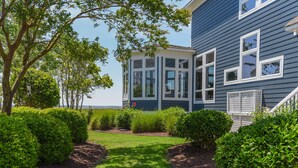 A modern house with a well-maintained garden, large windows, and a clear view of the sky.