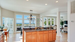 A spacious kitchen with a large island, wooden cabinets, and a view to the outside.
