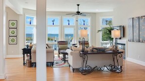 A spacious living room with a large window, a ceiling fan, and a fireplace.