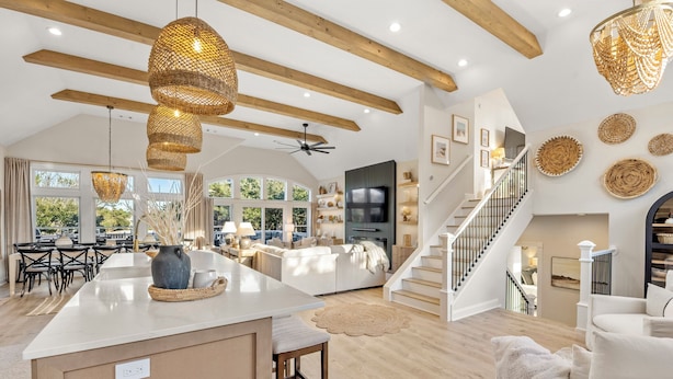 Amplia sala de estar con una isla grande, una escalera y un comedor con luz natural.