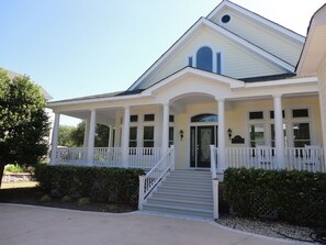 A two-story house with a covered porch, a front door, and a staircase leading to the entrance.