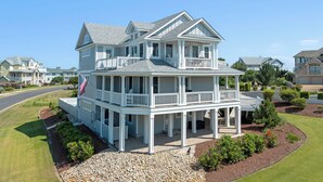 A two-story house with a balcony, a covered porch, and a flag. - It's 5 O'clock Somewhere: Pool, Spa, Club Access (Corolla)