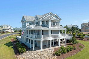 A two-story house with a balcony, a covered porch, and a flag.