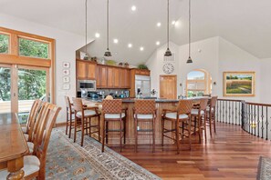 Una cocina amplia con armarios de madera, una isla central con taburetes de bar y un comedor con una mesa grande y sillas.