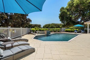 Relax by the pool surrounded by a clean deck, lounge chairs, and lush landscaping.